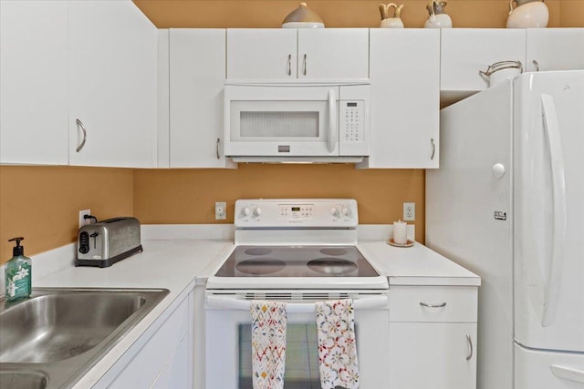 kitchen featuring light countertops, white appliances, and white cabinetry