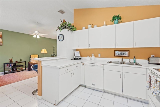 kitchen featuring visible vents, a ceiling fan, a sink, white appliances, and a peninsula