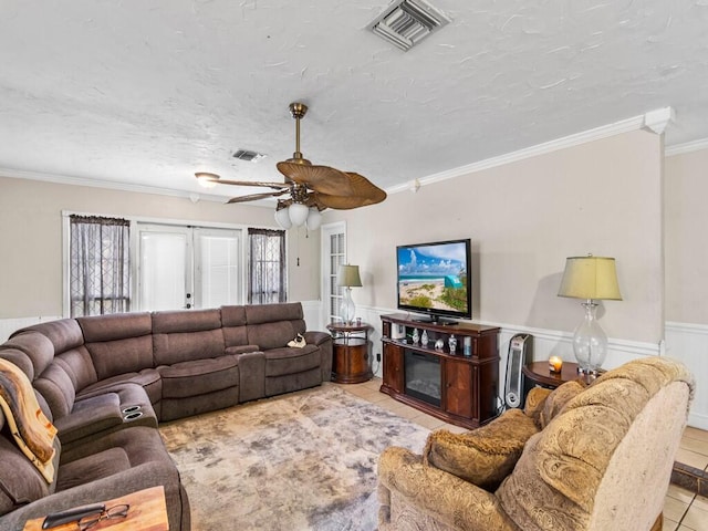 living room featuring a textured ceiling, french doors, ornamental molding, ceiling fan, and light tile patterned floors