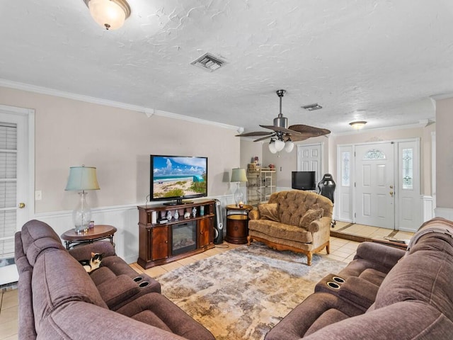 living room with a textured ceiling, ceiling fan, light tile patterned flooring, and ornamental molding