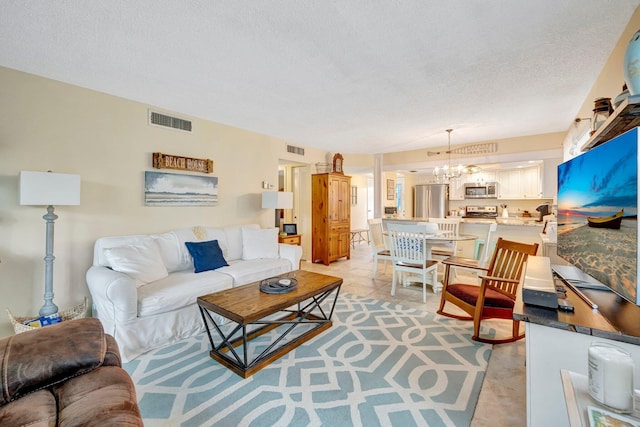 living area with visible vents, a notable chandelier, and a textured ceiling