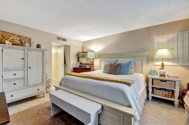 bedroom with a textured ceiling, light tile patterned flooring, and visible vents