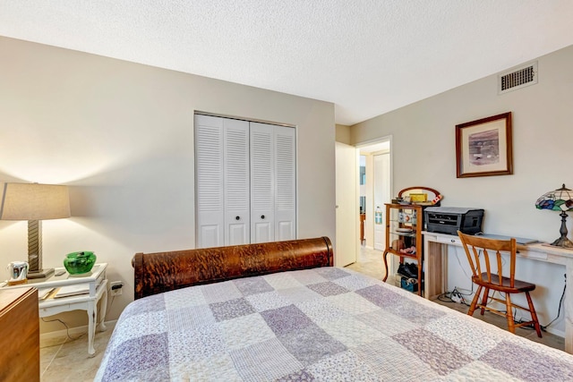 bedroom featuring baseboards, a textured ceiling, visible vents, and a closet