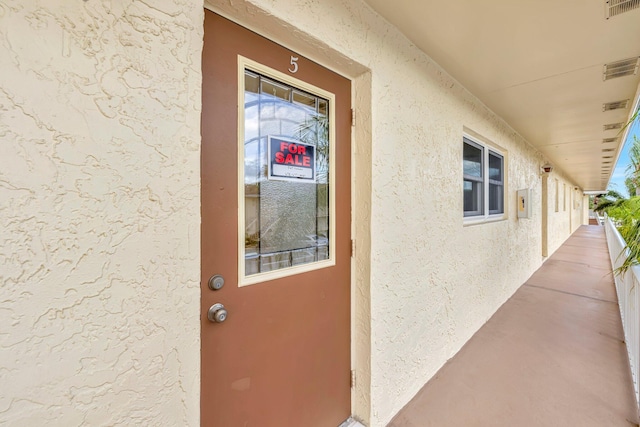 property entrance featuring a balcony, visible vents, and stucco siding