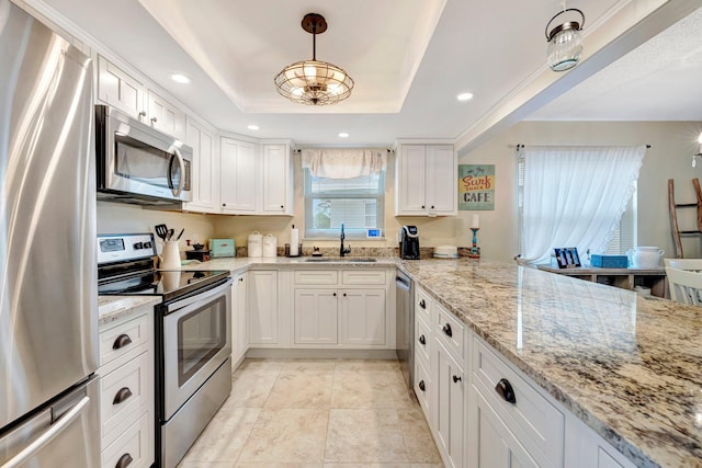 kitchen with white cabinets, a tray ceiling, stainless steel appliances, pendant lighting, and a sink