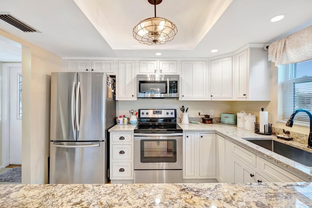 kitchen with stainless steel appliances, a sink, visible vents, white cabinets, and pendant lighting