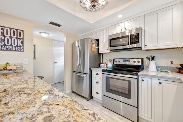 kitchen featuring stainless steel appliances, white cabinets, visible vents, and light stone countertops