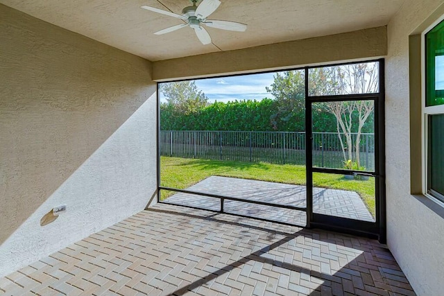 unfurnished sunroom featuring a healthy amount of sunlight and ceiling fan