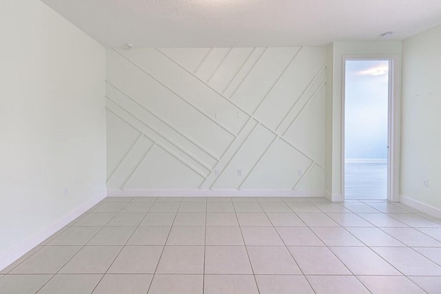 spare room featuring baseboards and light tile patterned floors