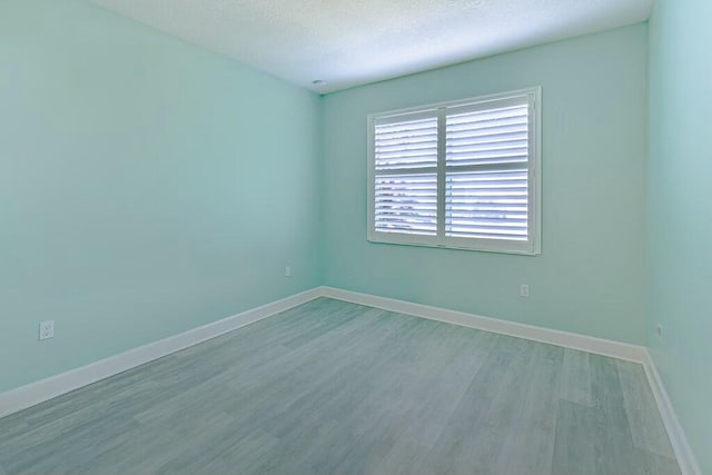 unfurnished room featuring light wood-type flooring and a textured ceiling