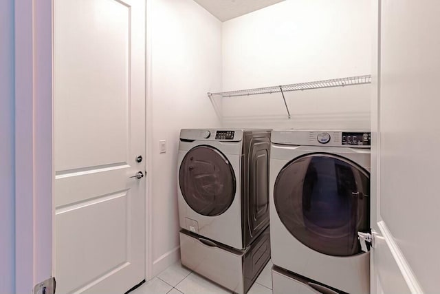 clothes washing area featuring washing machine and dryer and light tile patterned flooring