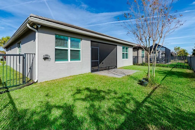 rear view of house featuring a patio area, stucco siding, and a yard