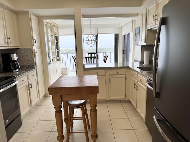 kitchen with light tile patterned floors, appliances with stainless steel finishes, tasteful backsplash, and light stone counters