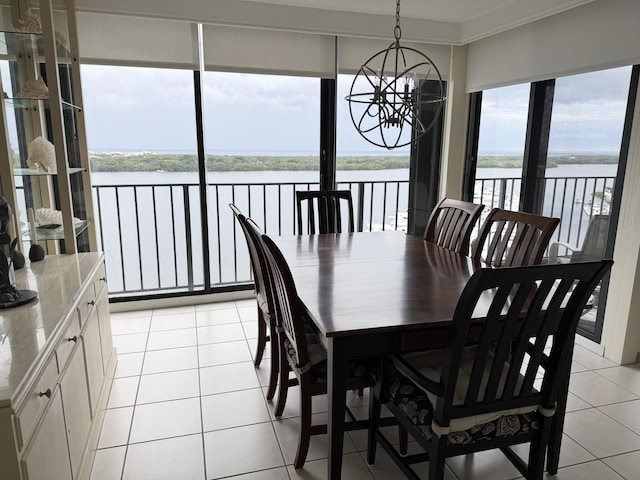 dining room with a water view, light tile patterned floors, a notable chandelier, and crown molding