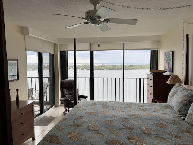 tiled bedroom with ceiling fan, a textured ceiling, access to outside, and a water view