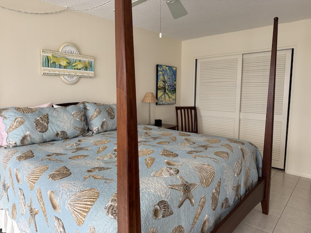 bedroom featuring ceiling fan, a textured ceiling, light tile patterned floors, and a closet