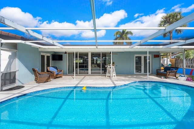 view of swimming pool with ceiling fan, a lanai, french doors, and a patio area