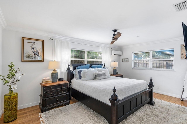 bedroom with ornamental molding, light hardwood / wood-style floors, an AC wall unit, and multiple windows