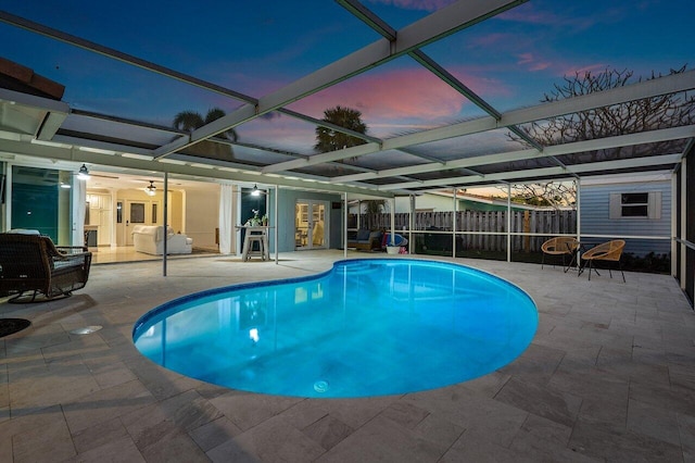 pool at dusk featuring a lanai and a patio area