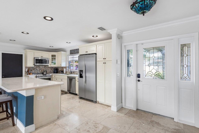 kitchen with a breakfast bar area, appliances with stainless steel finishes, crown molding, and kitchen peninsula