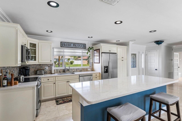 kitchen with appliances with stainless steel finishes, decorative backsplash, a kitchen island, light stone counters, and a breakfast bar