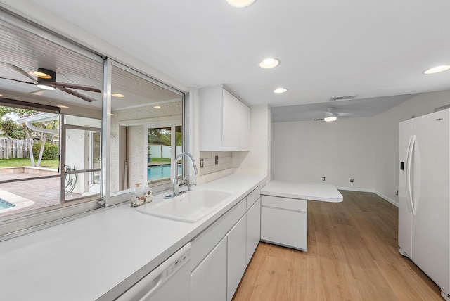 kitchen with decorative backsplash, sink, white appliances, white cabinetry, and light hardwood / wood-style flooring