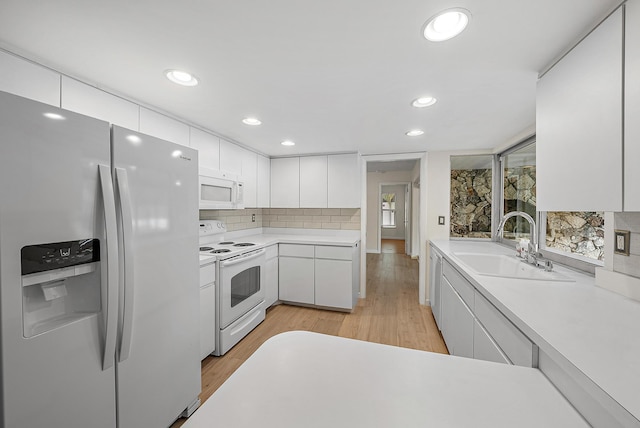 kitchen with sink, light hardwood / wood-style flooring, white cabinets, and white appliances