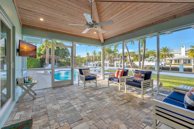 unfurnished sunroom featuring ceiling fan, wood ceiling, a wealth of natural light, and beamed ceiling