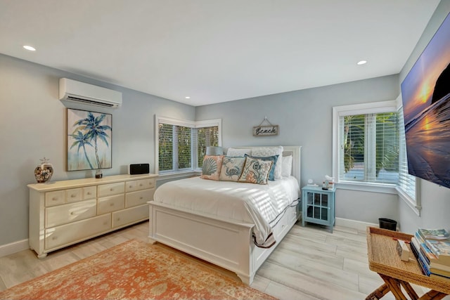 bedroom featuring multiple windows, a wall mounted AC, and light wood-type flooring