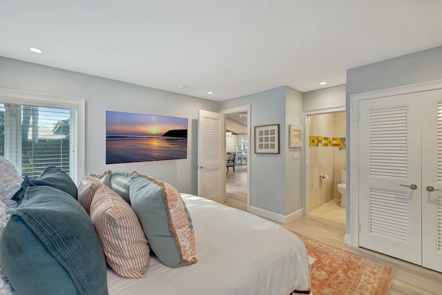 bedroom featuring ensuite bathroom and light hardwood / wood-style floors