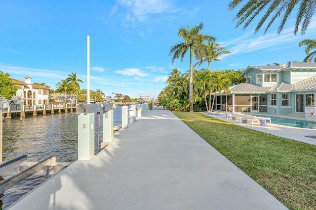 dock area featuring a water view, a lawn, and a patio area