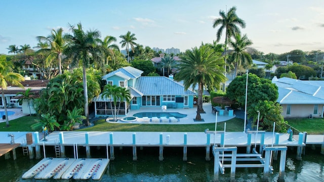 back of property with a water view, a lawn, a patio, and a sunroom