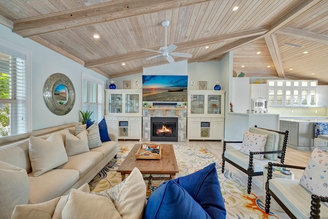 living room featuring lofted ceiling with beams, wood ceiling, a tiled fireplace, and light hardwood / wood-style flooring