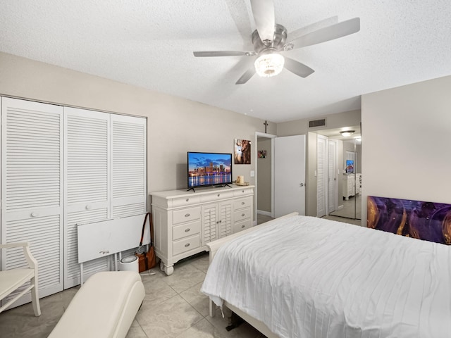 tiled bedroom with a textured ceiling and ceiling fan