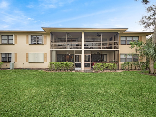 back of property featuring ceiling fan and a lawn