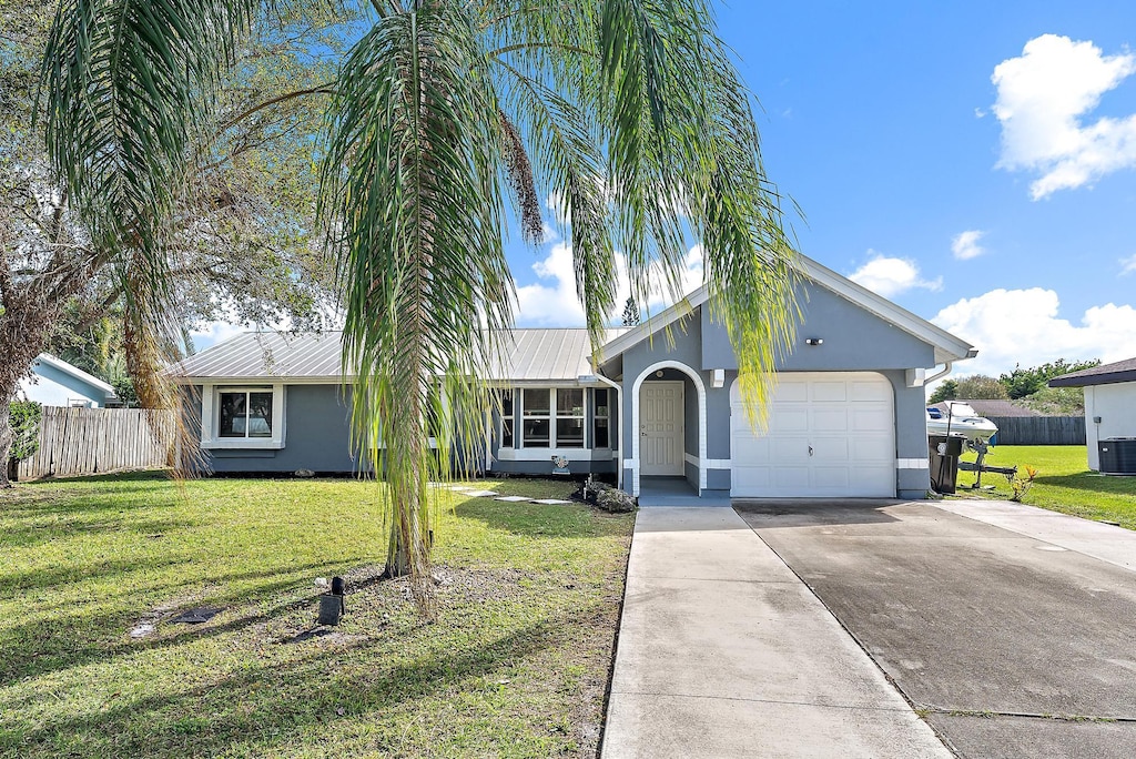 single story home with a garage, a front lawn, and central AC unit