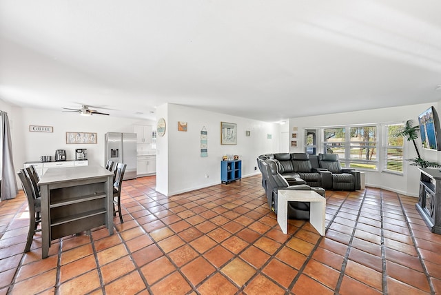 living area featuring ceiling fan, baseboards, and light tile patterned flooring