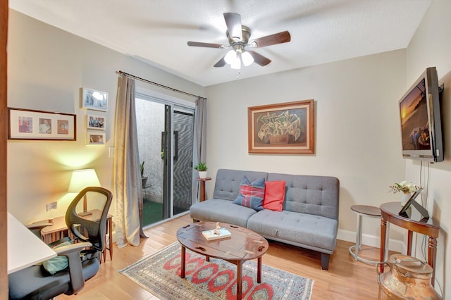 living room featuring ceiling fan, a textured ceiling, and light wood-type flooring