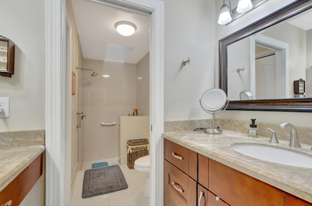 bathroom with vanity, toilet, tile patterned flooring, and tiled shower