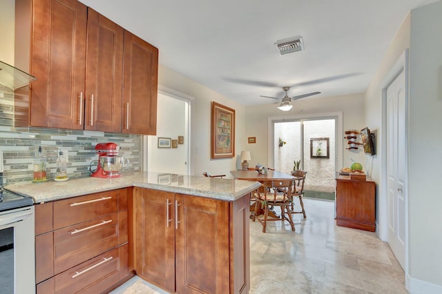 kitchen featuring stainless steel range with electric cooktop, tasteful backsplash, ceiling fan, kitchen peninsula, and light stone counters