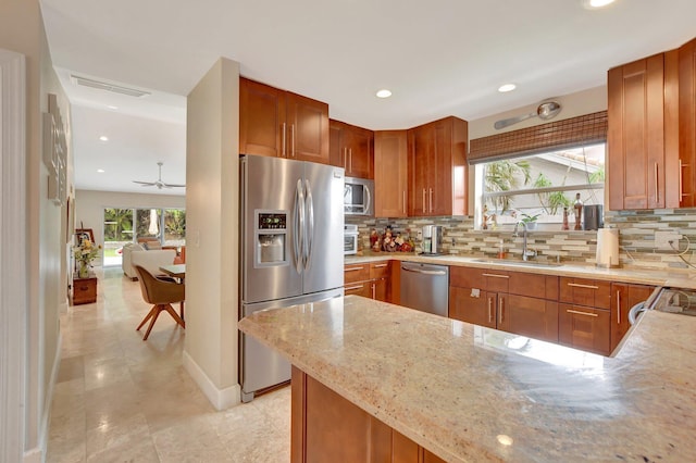 kitchen with stainless steel appliances, light stone counters, tasteful backsplash, and sink