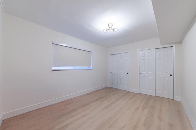 unfurnished bedroom with two closets and light wood-type flooring