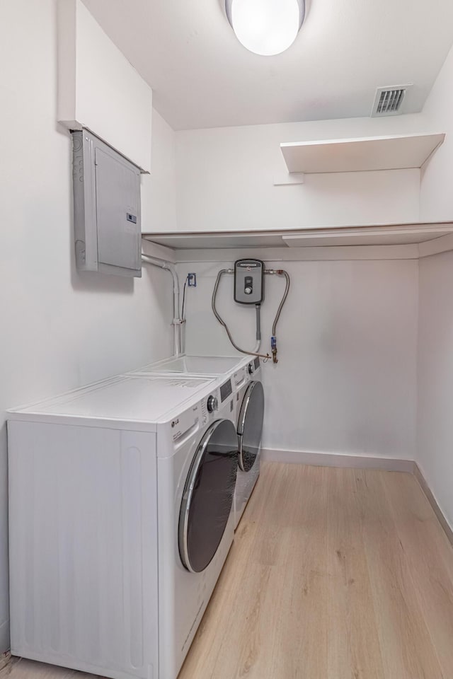 laundry room featuring separate washer and dryer, electric panel, and light hardwood / wood-style floors