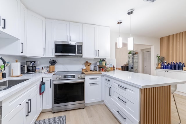 kitchen with pendant lighting, sink, appliances with stainless steel finishes, white cabinets, and kitchen peninsula