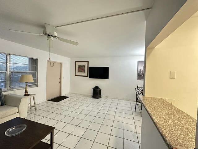 tiled living room with ceiling fan with notable chandelier