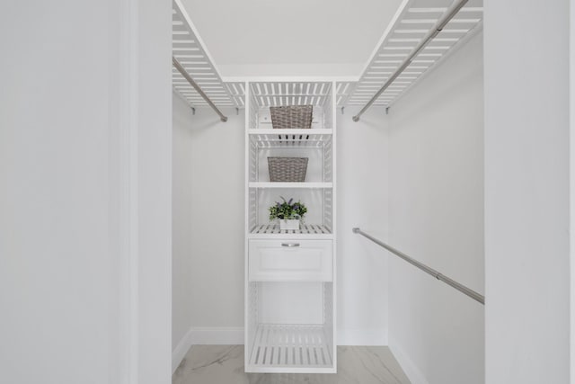 walk in closet featuring marble finish floor