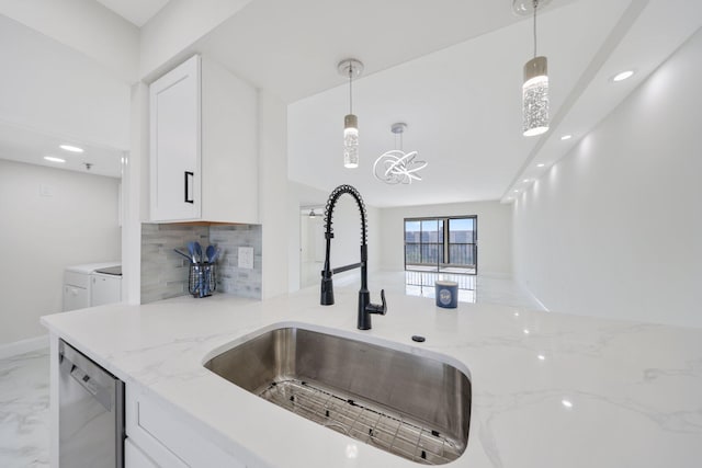 kitchen featuring separate washer and dryer, white cabinets, sink, hanging light fixtures, and stainless steel dishwasher