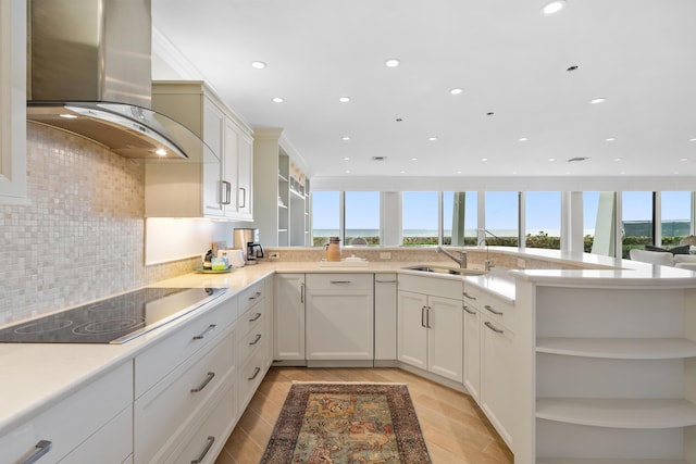 kitchen with wall chimney range hood, kitchen peninsula, sink, white cabinets, and black electric cooktop