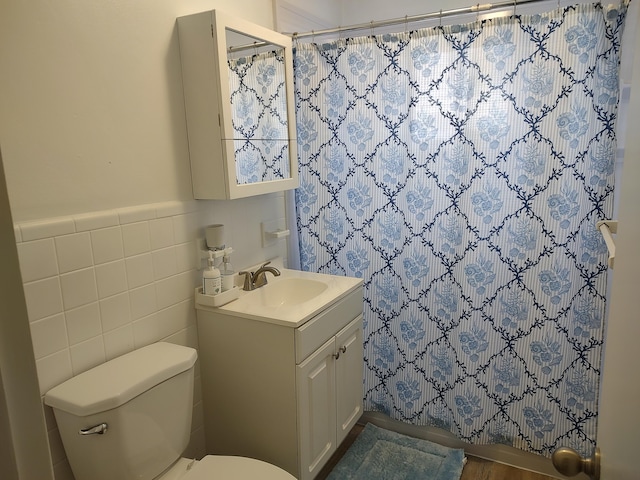 bathroom with toilet, vanity, and tile walls