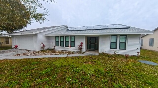 ranch-style house with a garage, a front lawn, solar panels, and a porch